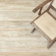 a chair sitting on top of a wooden floor next to a white wall and tile floor