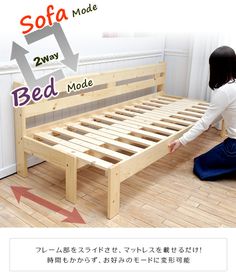 a woman kneeling on the floor next to a bed frame