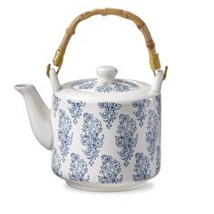 a blue and white teapot with bamboo handle on it's side, decorated with floral designs