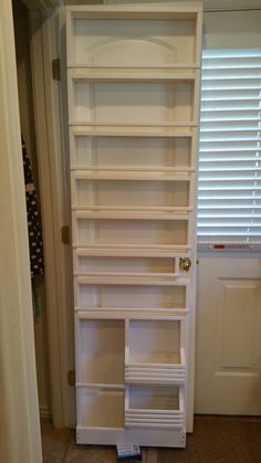 a white book shelf sitting in the corner of a room next to a door and window