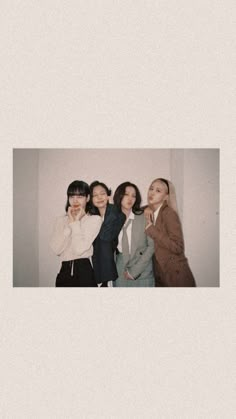 four women standing next to each other in front of a white wall