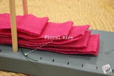 a pile of pink cloth sitting on top of a piece of gray metal with a needle in it