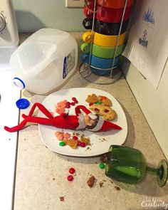 the elf is eating his food on the counter next to the water bottle and candy