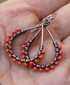 a pair of red beaded hoop earrings sitting on top of a hand held palm