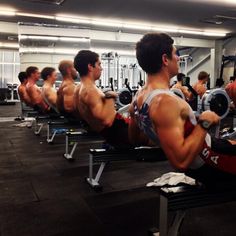 a group of men working out in the gym with dumbbells on their back