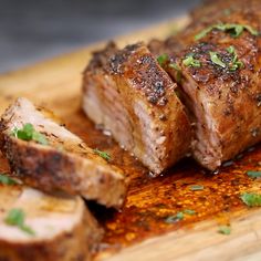 some meat on a wooden cutting board with parsley sprinkled around it and sliced into pieces