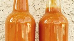 two orange bottles sitting next to each other on top of a cement wall and floor