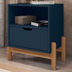 a night stand with two drawers and a book on top, next to a couch