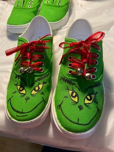 two green shoes with red laces on them sitting on a white sheeted surface