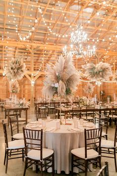 an indoor venue with tables, chairs and chandeliers in the middle of it