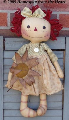 a doll with red hair is sitting on a wooden crate and has a sunflower in it's hand