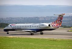 an airplane is parked on the runway with mountains in the background and grass to the side