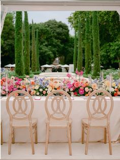 four chairs sitting in front of a table with flowers and greenery on the side