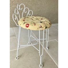 a white metal stool with a flowered seat cover on it's backrest