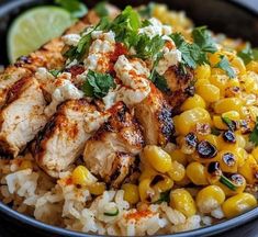 a bowl filled with chicken, corn and rice next to a lime wedge on the side