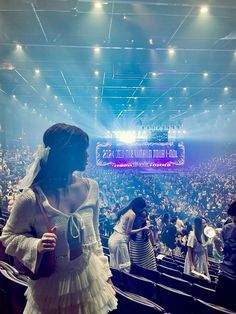 a woman is standing in front of an audience at a concert or show wearing a white dress