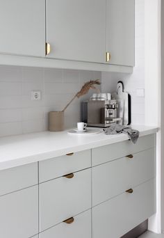 a kitchen with white cabinets and gold handles