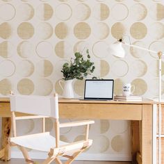 a laptop computer sitting on top of a wooden desk next to a white chair and lamp