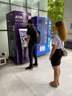 two people standing in front of atm machines