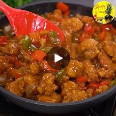 a pan filled with chicken and peppers being stirred by a red spatula on top of it