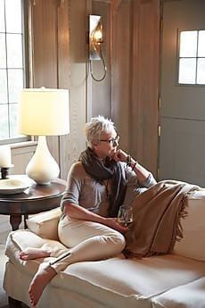 an older woman sitting on a couch talking on the phone