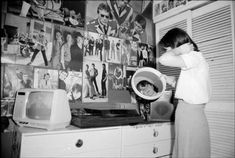 a woman standing in front of a dresser holding a hair dryer over her head