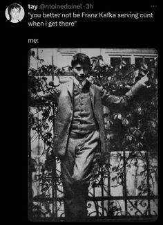 a black and white photo of a man with his arms outstretched in front of a fence