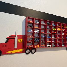 a red toy truck is mounted to the wall with shelves full of cars on it