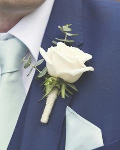 a man wearing a blue suit and tie with a white rose boutonniere