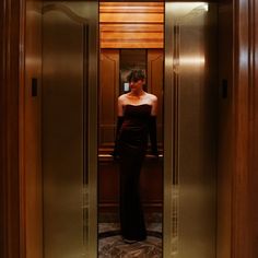 a woman is standing in an elevator wearing a black dress