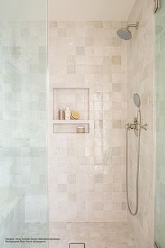 a walk in shower sitting next to a tiled wall