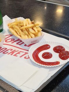 a tray with french fries and ketchup on it next to a bottle of beer