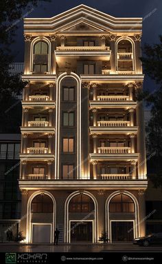 an illuminated building at night in the middle of town, with lights on it's balconies