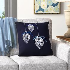 two decorative ornaments hanging from strings on a pillow in front of a couch with blue throw pillows