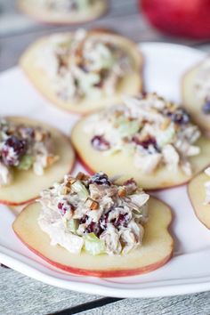 small appetizers are arranged on a plate with apples in the backgroud