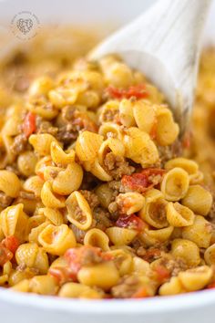 a spoon full of pasta and meat in a white bowl