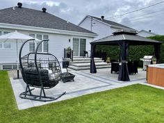 a backyard with a hot tub, gazebo and patio furniture on the grass area