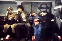 four people sitting on a subway train with their heads resting against each other's backs