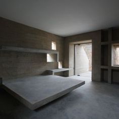 an empty room with concrete walls and shelves on either side of the door, looking out onto mountains