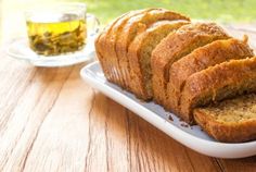 slices of banana bread on a plate next to a cup of tea and glass of green tea