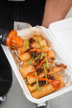 someone pouring sauce on some food in a container