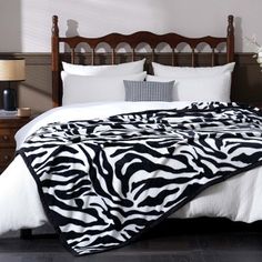 a zebra print blanket on top of a bed in a room with black and white decor