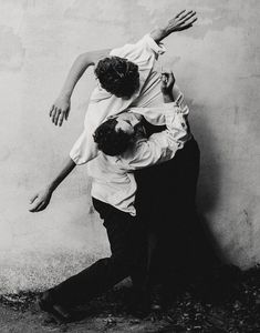 black and white photograph of two people leaning against a wall with their arms around each other