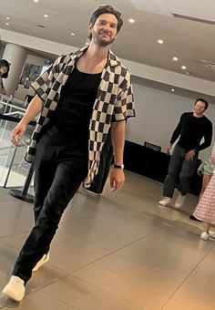 a man in black and white checkered shirt is walking through an airport with other people