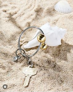 a keychain on the sand with shells and seashells attached to it