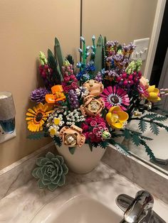 a vase filled with colorful flowers sitting on top of a bathroom sink next to a mirror