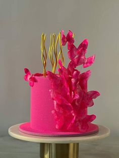 a pink and gold cake with flowers on top