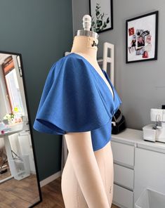 a mannequin wearing a blue top in front of a mirror