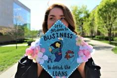 a woman holding up a blue graduation cap that says let's get down to business