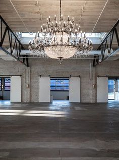 an empty warehouse with several doors and a chandelier hanging from the ceiling